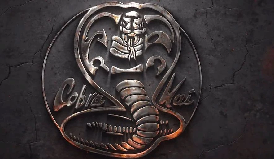 A cobra made out of medal with the words Cobra Kai beside it.